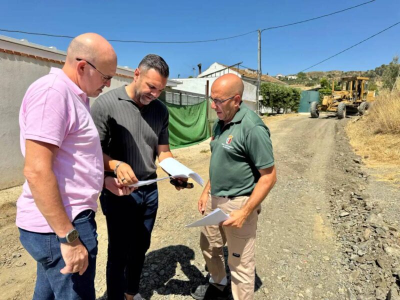 Obras de acondicionamiento de un camino rural en Cártama, con maquinaria extendiendo zahorra sobre el firme