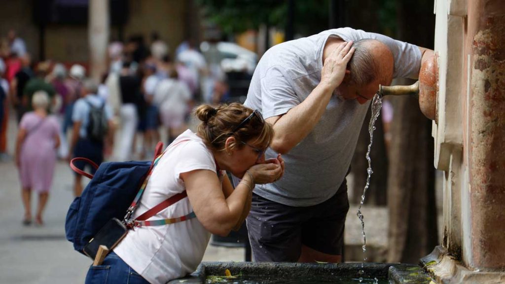 Personas refrescándose en una fuente pública durante la ola de calor en Andalucía